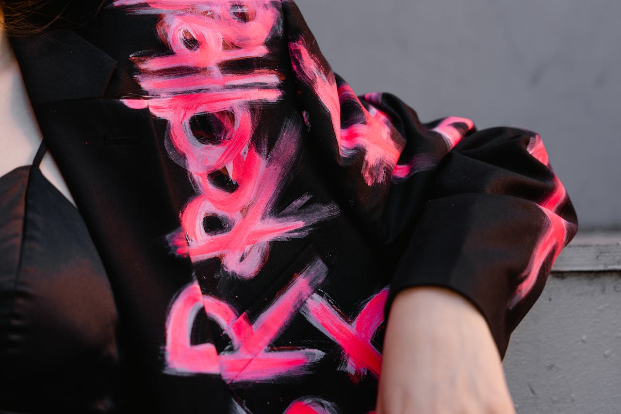 services-03 Detailed close-up of a black blazer with vibrant hand-painted abstract art design in pink.
